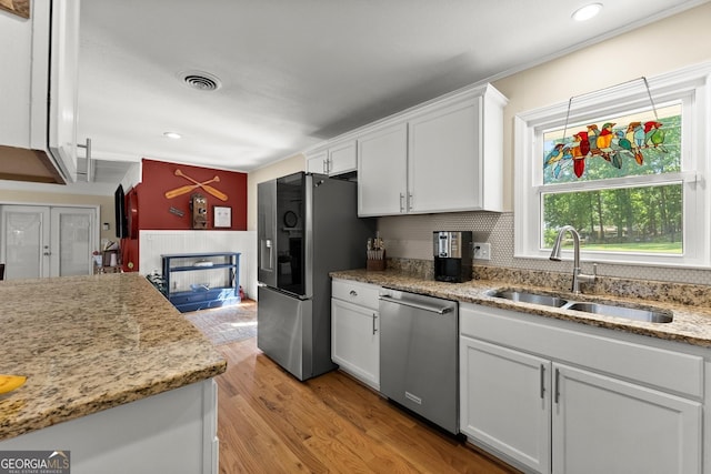 kitchen featuring decorative backsplash, visible vents, a sink, stainless steel appliances, and white cabinetry
