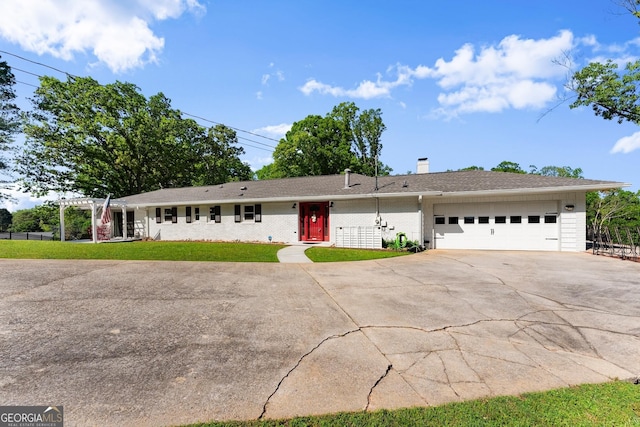 ranch-style home featuring a front yard, a chimney, brick siding, concrete driveway, and an attached garage