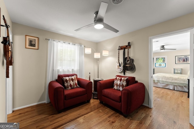 living area with baseboards, ceiling fan, and wood finished floors