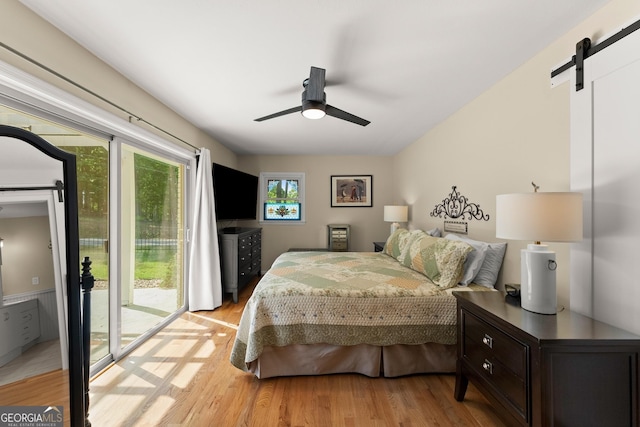 bedroom featuring access to outside, a barn door, and light wood-type flooring