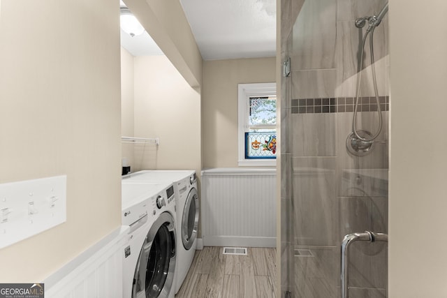 washroom featuring washing machine and clothes dryer, laundry area, wainscoting, and light wood-style floors