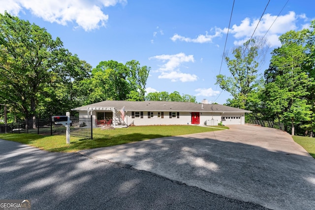 ranch-style house featuring a chimney, a front yard, fence private yard, aphalt driveway, and an attached garage