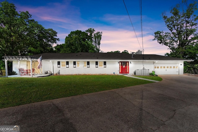 ranch-style home featuring a garage, a yard, concrete driveway, and brick siding