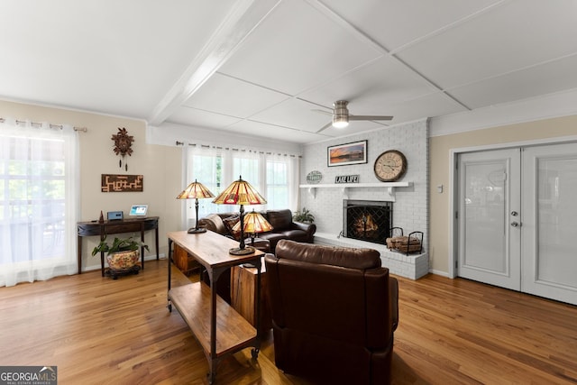 living area with baseboards, a brick fireplace, ceiling fan, and wood finished floors