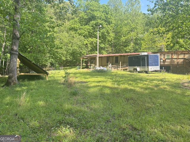 view of yard featuring a deck and a view of trees