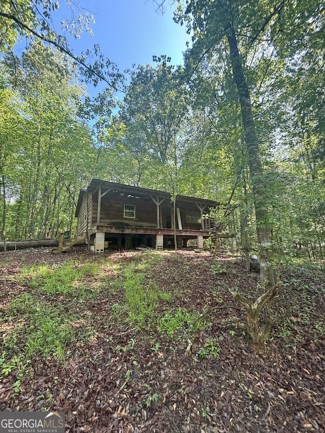 back of property featuring a wooden deck and a wooded view
