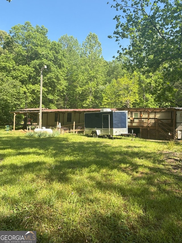 exterior space featuring a yard, a deck, and an outbuilding