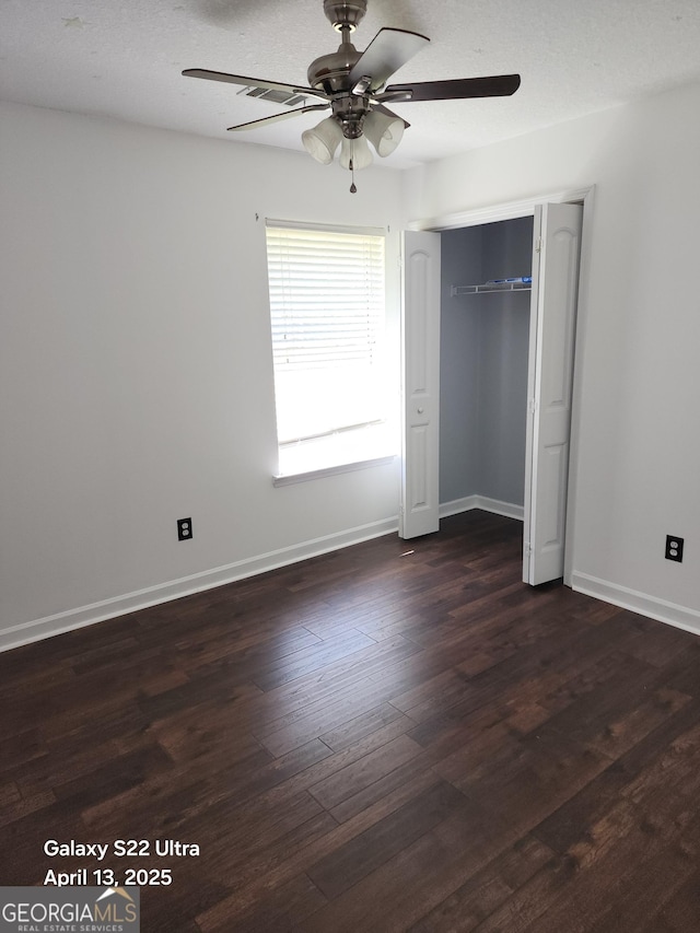 unfurnished bedroom with visible vents, a closet, baseboards, dark wood-type flooring, and a ceiling fan