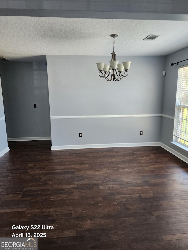 unfurnished room with visible vents, an inviting chandelier, baseboards, dark wood-type flooring, and a textured ceiling