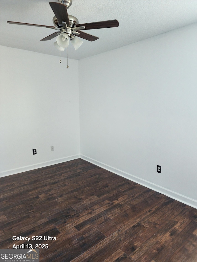 empty room with baseboards, ceiling fan, and dark wood finished floors