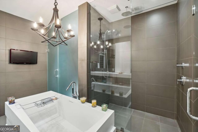 bathroom featuring walk in shower, a soaking tub, a notable chandelier, and tile walls