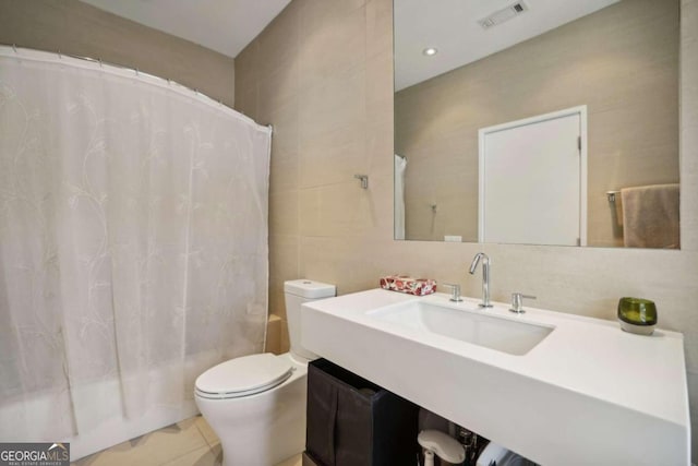 bathroom with visible vents, tile patterned flooring, toilet, tile walls, and shower / tub combo