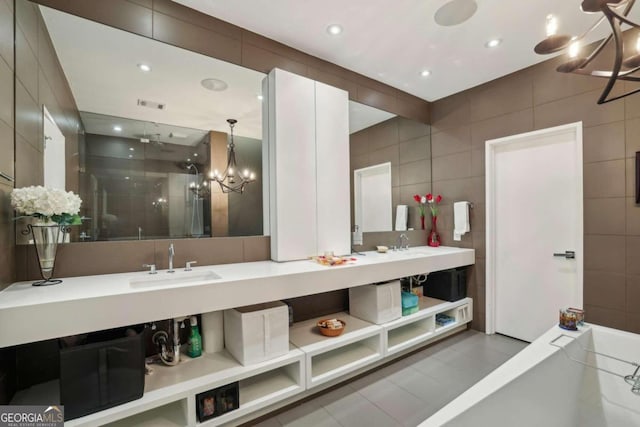 full bathroom featuring a sink, tile walls, double vanity, and a notable chandelier
