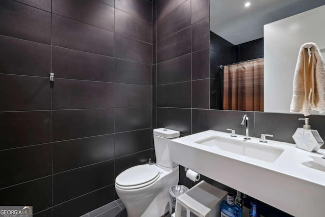 full bathroom with a sink, tile walls, toilet, and curtained shower