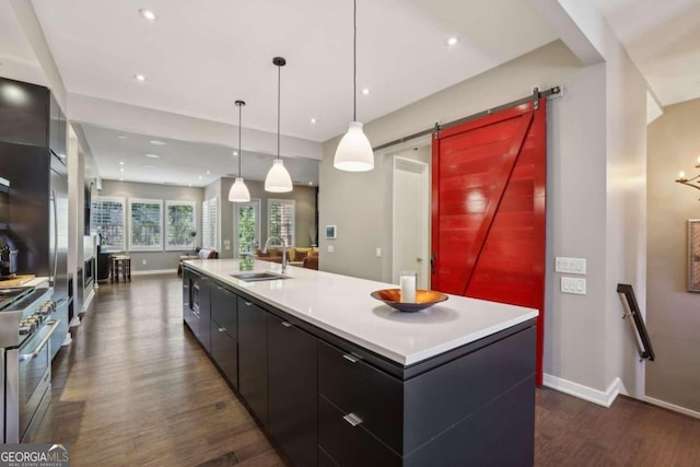 kitchen with modern cabinets, dark wood finished floors, a barn door, a sink, and stainless steel gas range