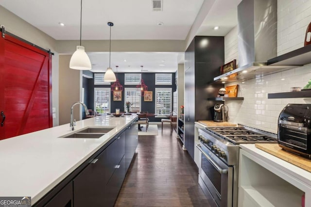 kitchen with visible vents, a sink, light countertops, stainless steel range, and wall chimney exhaust hood