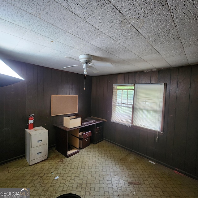 office area with wooden walls, tile patterned floors, and ceiling fan