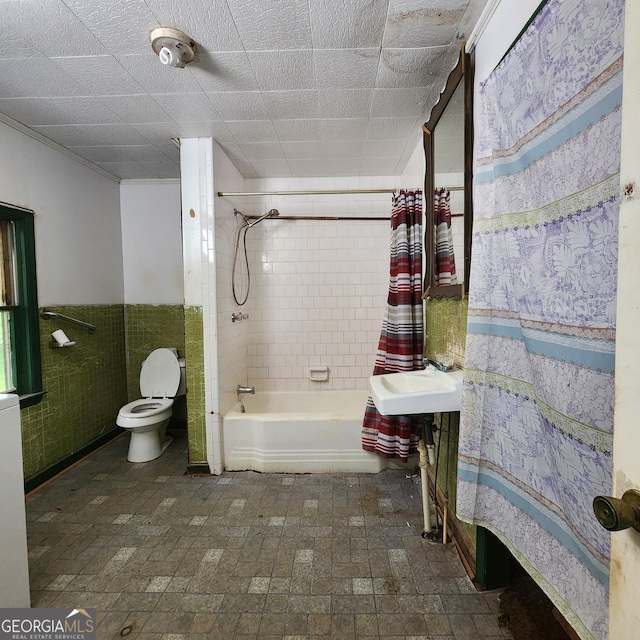 bathroom with a sink, a wainscoted wall, shower / bath combo, and toilet