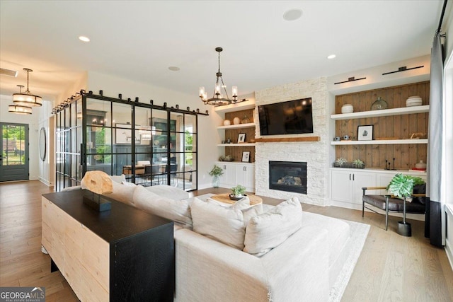 3525 Brynhurst Dr, Cumming, GA 30028 - living area featuring wood finished floors, built in features, an inviting chandelier, baseboards, and a stone fireplace