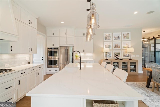 3525 Brynhurst Dr, Cumming, GA 30028 - kitchen with appliances with stainless steel finishes, hanging light fixtures, white cabinetry, backsplash, and a large island with sink