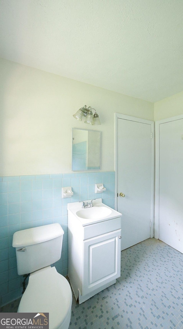 120 Hunt Rd, Athens, GA 30606 - half bath featuring a textured ceiling, tile walls, wainscoting, vanity, and toilet