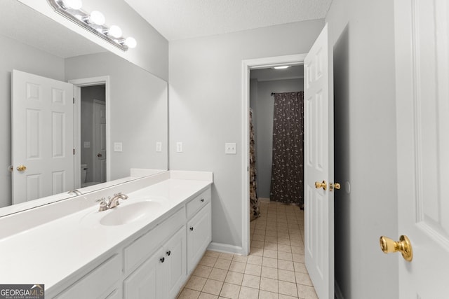 bathroom featuring vanity, toilet, a textured ceiling, tile patterned floors, and baseboards