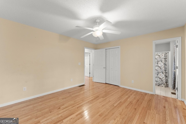 unfurnished bedroom with light wood-type flooring, connected bathroom, baseboards, and visible vents