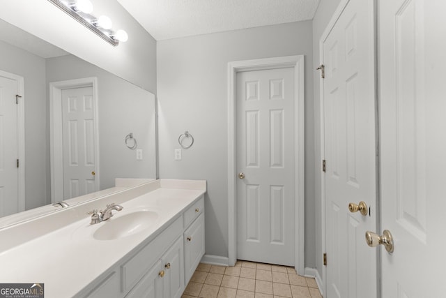 bathroom with a textured ceiling, tile patterned floors, baseboards, and vanity