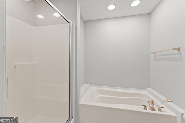 bathroom with a shower stall, a garden tub, and recessed lighting