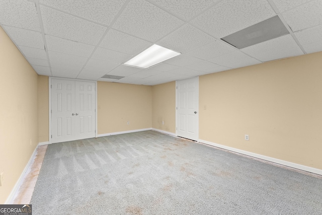 finished below grade area with baseboards, a drop ceiling, and carpet