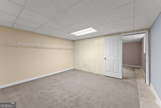 finished basement featuring baseboards, a paneled ceiling, and carpet