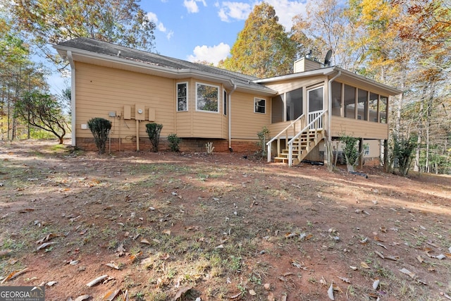 rear view of house with a chimney and a sunroom