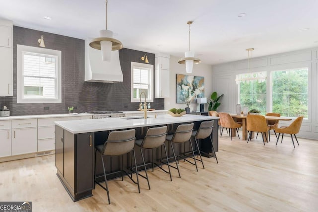 kitchen with backsplash, white cabinetry, and a sink