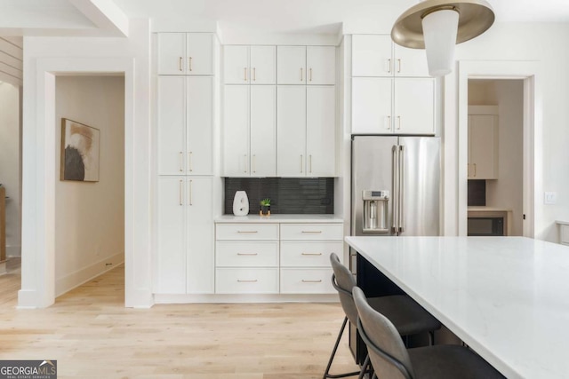 kitchen featuring white cabinets, light wood-type flooring, and high end fridge
