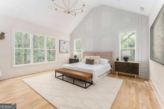 bedroom with an inviting chandelier, multiple windows, and light wood finished floors
