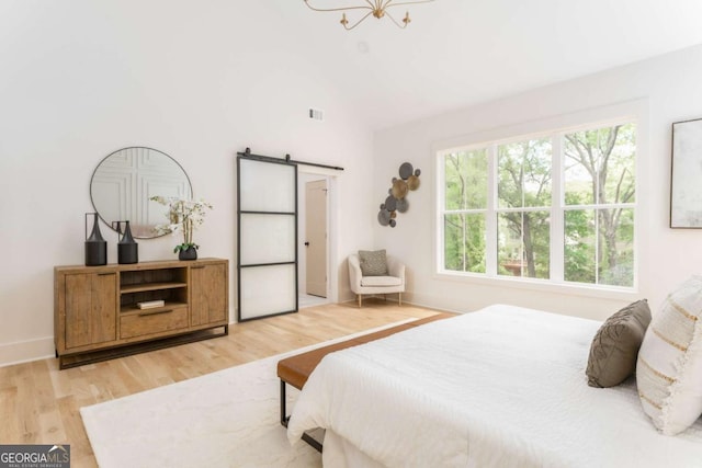 bedroom with visible vents, a barn door, light wood finished floors, lofted ceiling, and an inviting chandelier