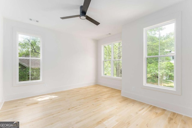 unfurnished room with baseboards, a ceiling fan, wood finished floors, and visible vents