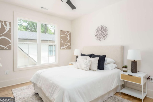 bedroom with baseboards, ceiling fan, wood finished floors, and visible vents
