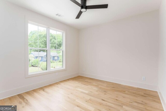 empty room with visible vents, a ceiling fan, light wood finished floors, and baseboards
