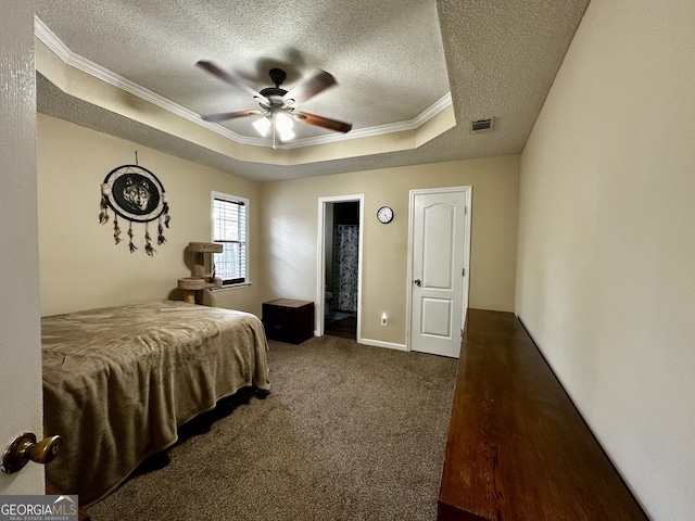 bedroom featuring crown molding, a textured ceiling, a tray ceiling, and visible vents