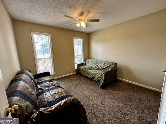 carpeted living room with baseboards, a textured ceiling, and ceiling fan