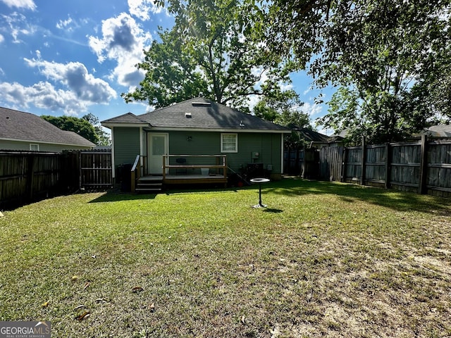 rear view of house with a lawn, a deck, and a fenced backyard