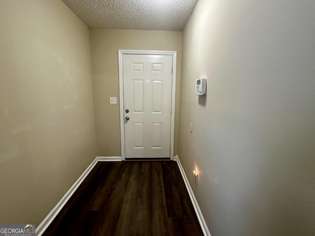 entryway with dark wood-style flooring, a textured ceiling, and baseboards