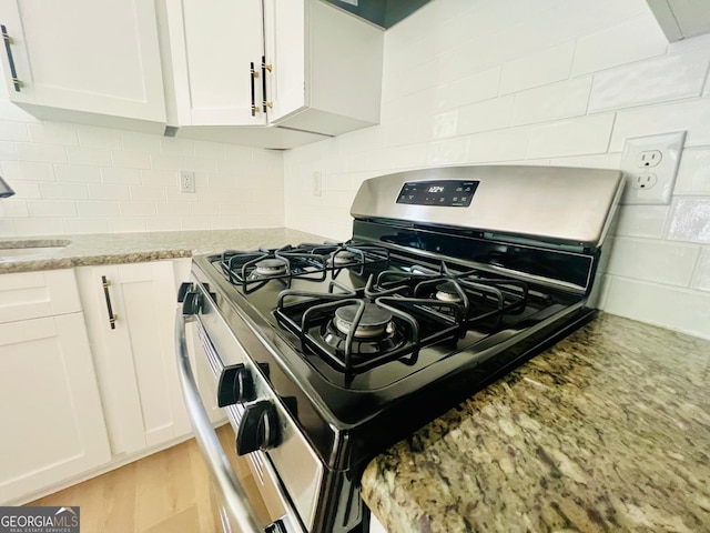 2502 Barge Rd SW, Atlanta, GA 30331 - room details featuring stainless steel range with gas stovetop, white cabinets, light stone counters, and decorative backsplash
