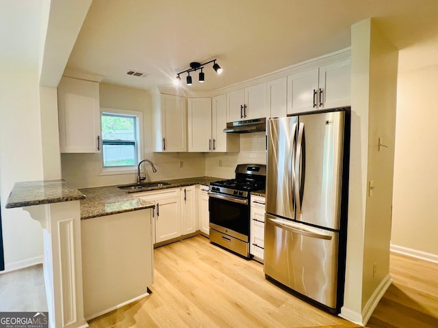 2502 Barge Rd SW, Atlanta, GA 30331 - kitchen with white cabinetry, under cabinet range hood, a sink, dark stone countertops, and appliances with stainless steel finishes