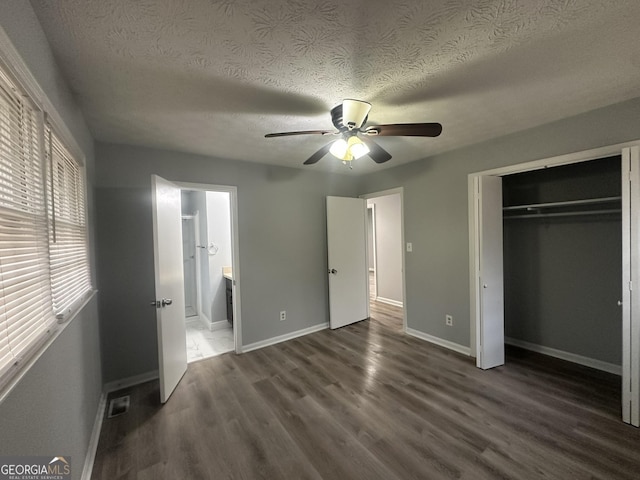 unfurnished bedroom with baseboards, a textured ceiling, wood finished floors, and a closet
