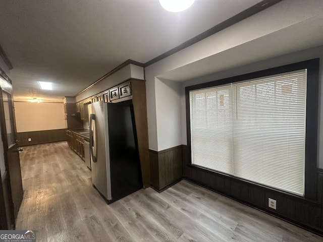 kitchen with wooden walls, light wood-style floors, freestanding refrigerator, and wainscoting