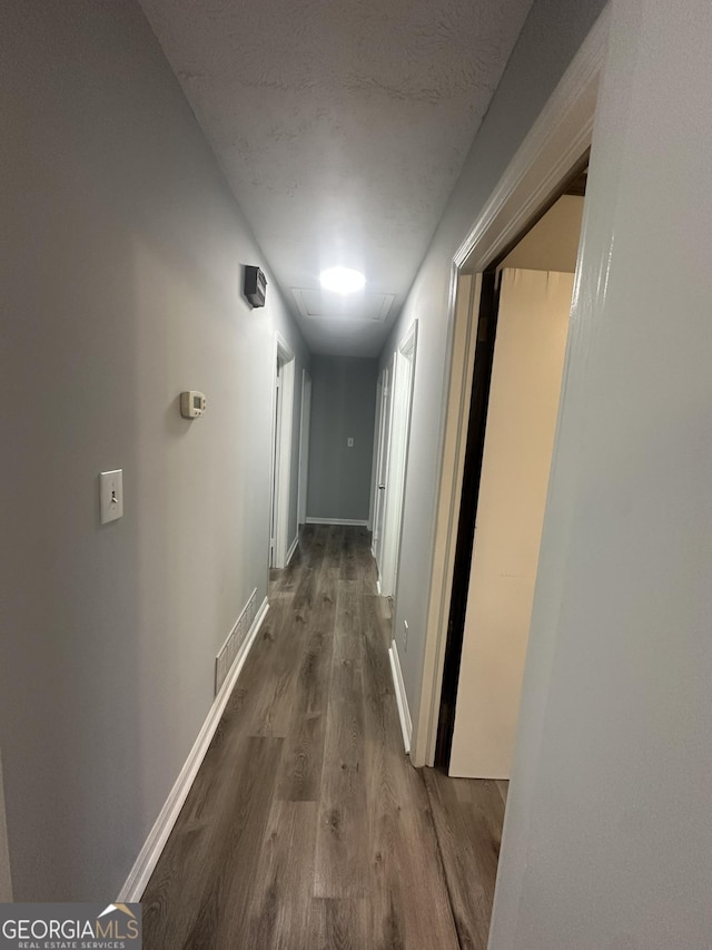hall with baseboards, wood finished floors, and visible vents