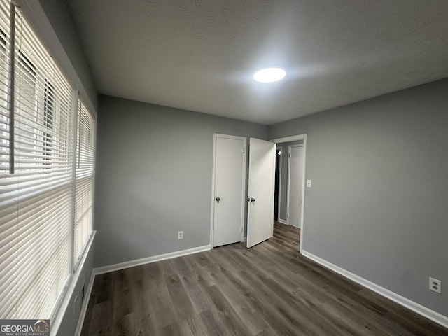 unfurnished bedroom featuring dark wood-type flooring and baseboards