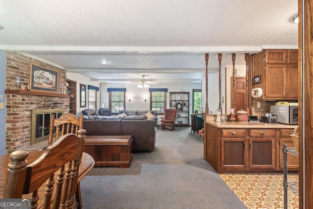 living area featuring light colored carpet, ceiling fan, beam ceiling, and a fireplace